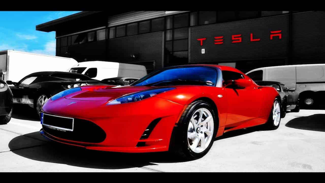 Tesla red car and logo in the background