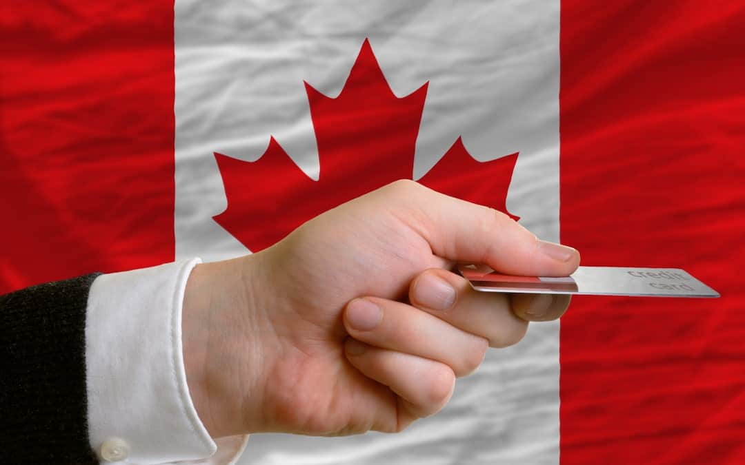 a man holding a credit card in his hand with a Canadian flag in the background