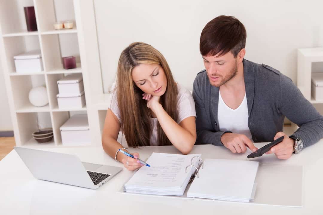 a young couple sitting at the table and calculating