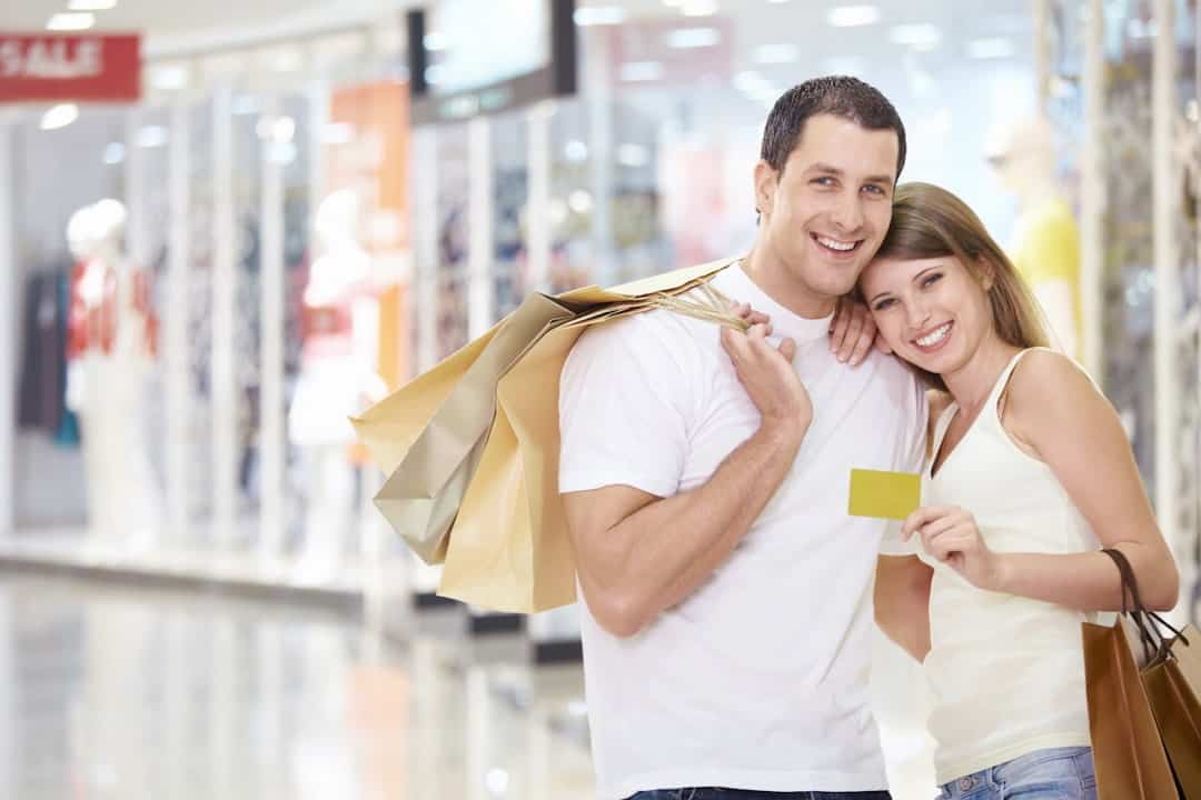 a smiling couple with a credit card and shopping bags