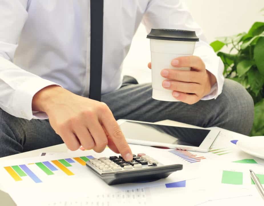 a man using a calculator with a cup of coffee in one hand