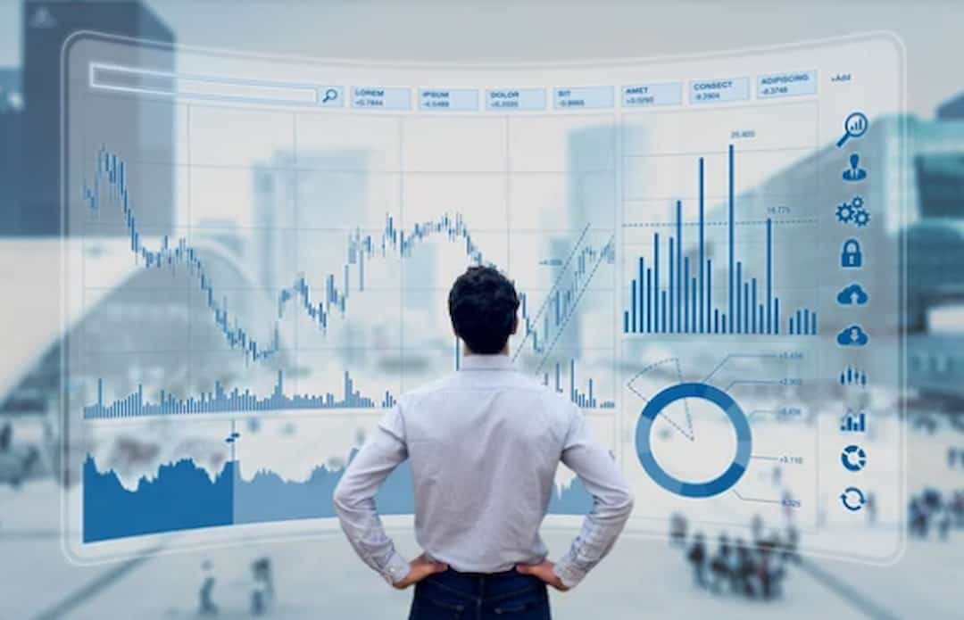 a man standing in front of the large screen with stock data