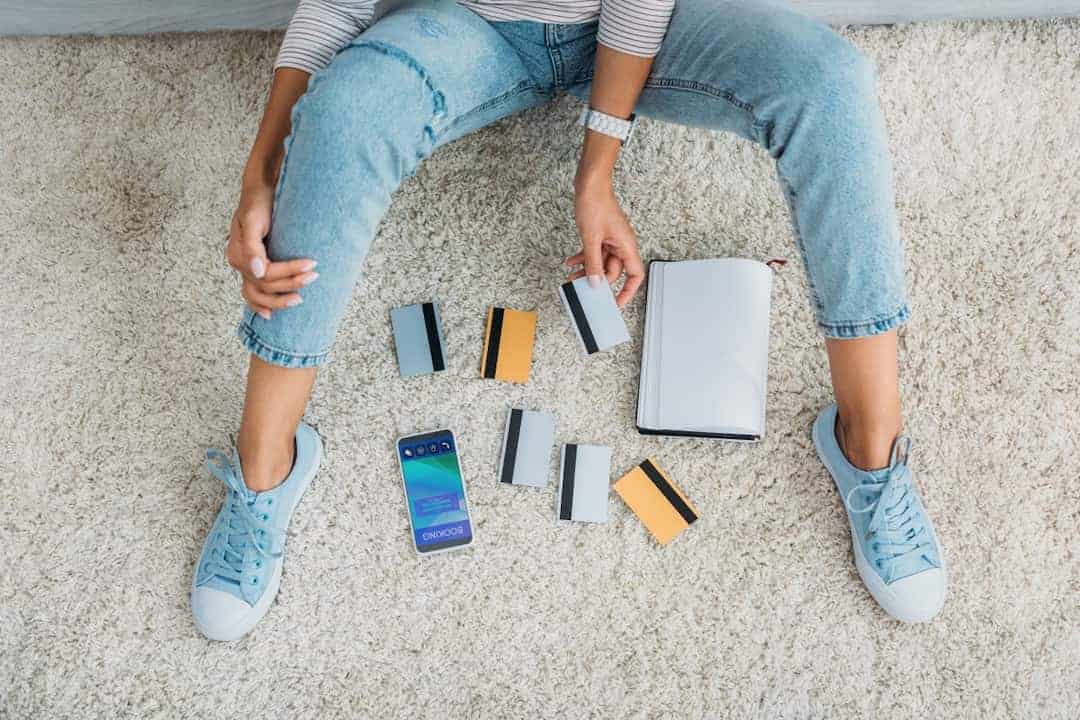 Partial view of woman sitting on floor with notebook, smartphone and credit cards