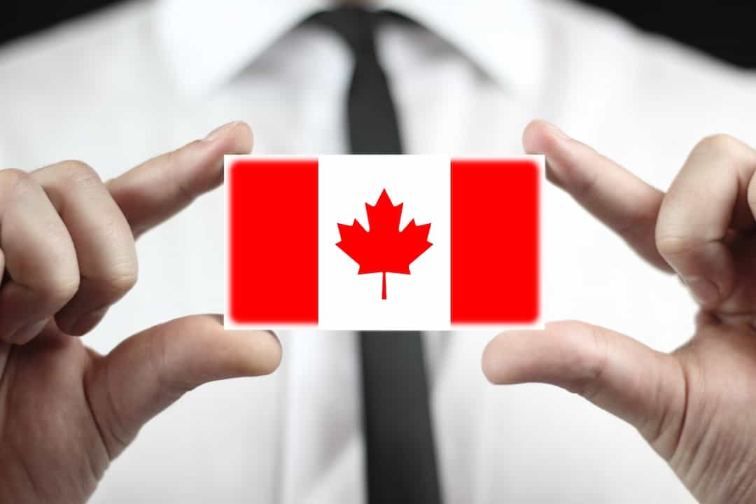 a man holding credit card with Canadian flag between his fingers