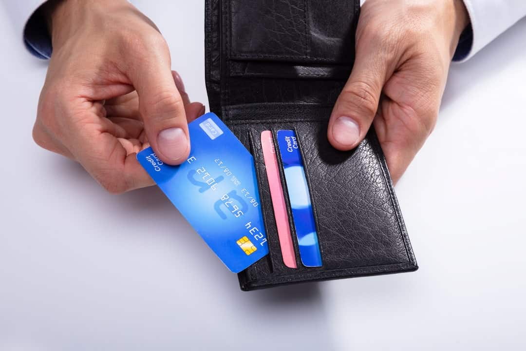 a man holding a wallet with credit cards in his hands