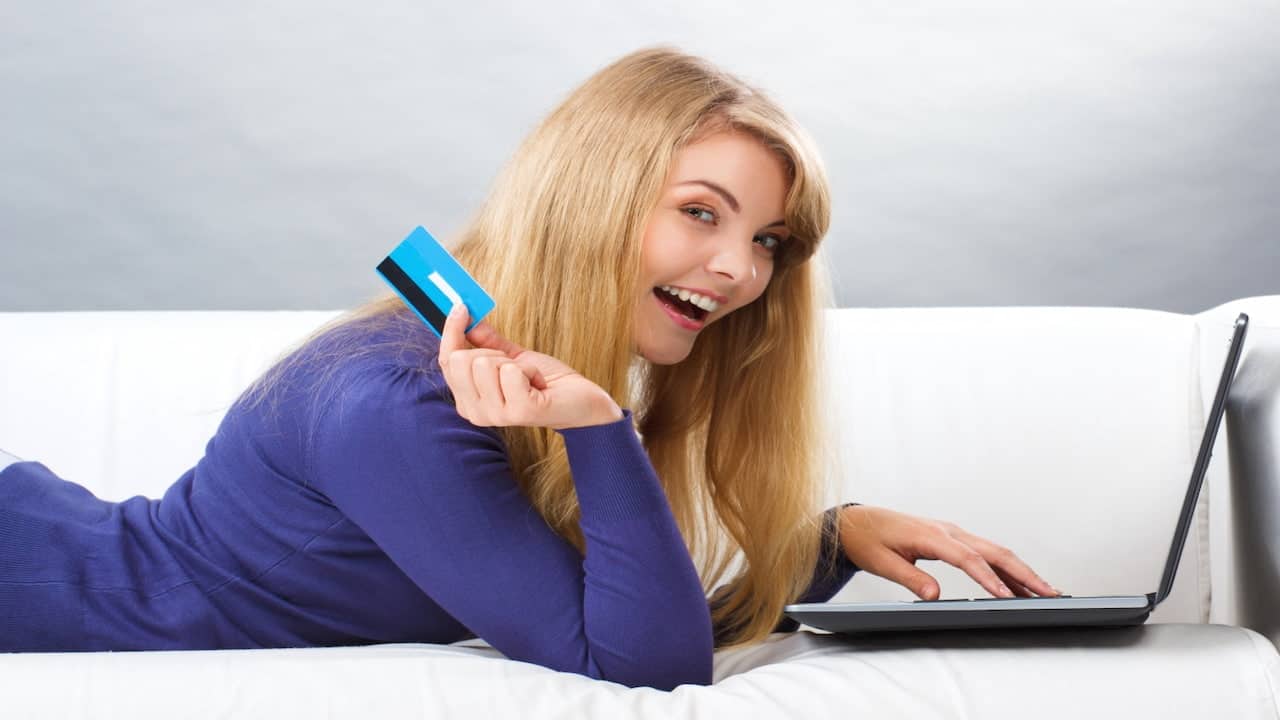 a woman holding a credit card in front of her laptop