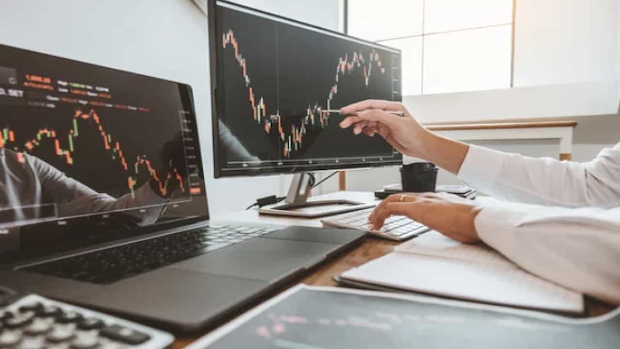 a person watching the stock graphs on two monitors