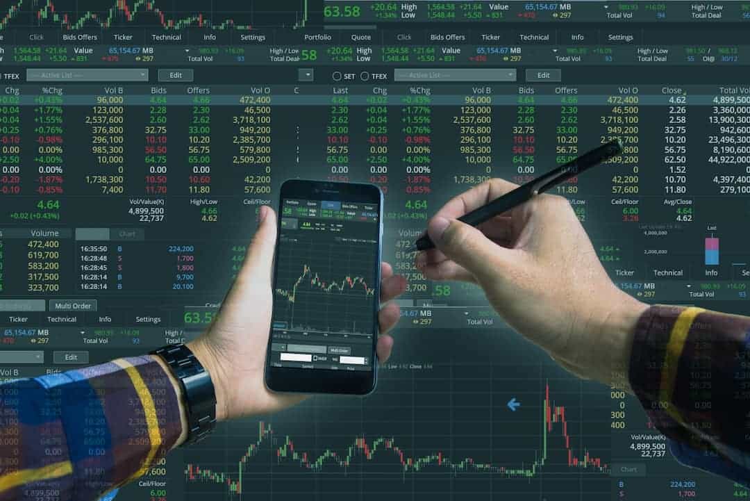 a person using a cellphone for stock trading with a big stock board in the background