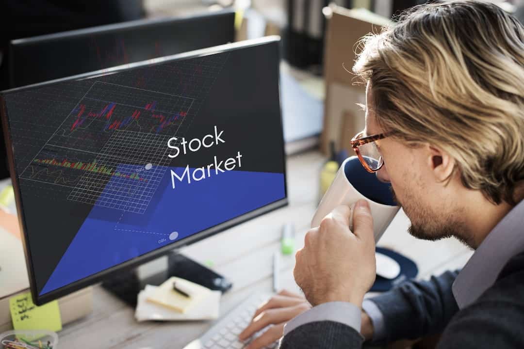 a man in front of the monitor with stock trading platform displayed