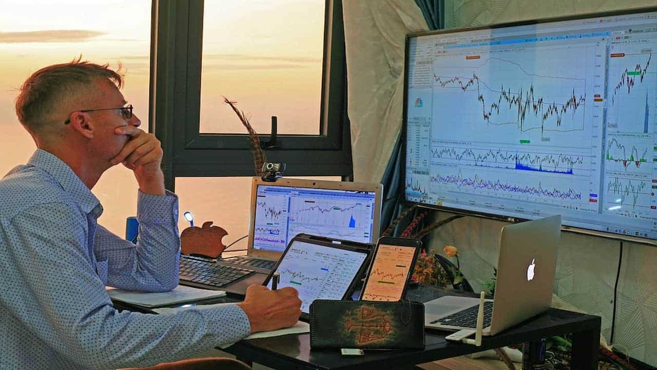 a man watching the stock graphs n monitors