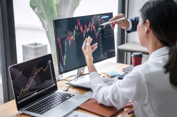 two people watching the stock graph on the monitor