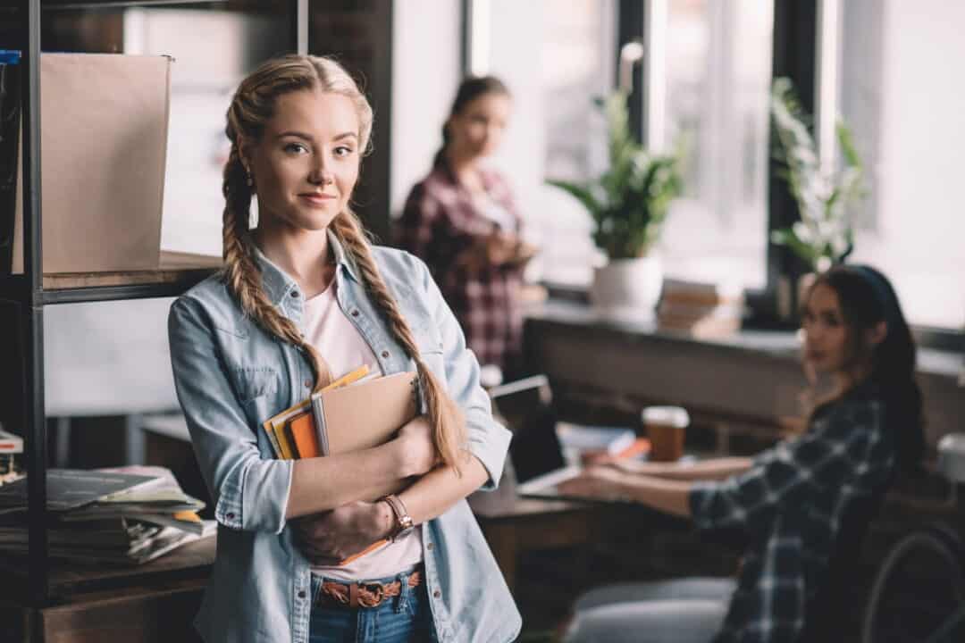 a blonde student girl with two colleagues in the background