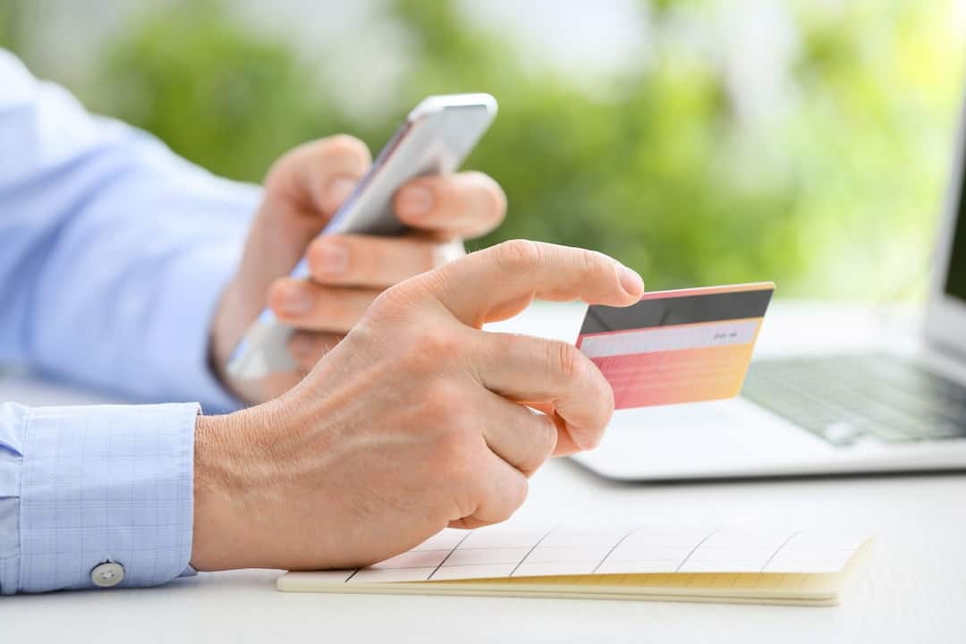 a man holding a credit card and a cellphone