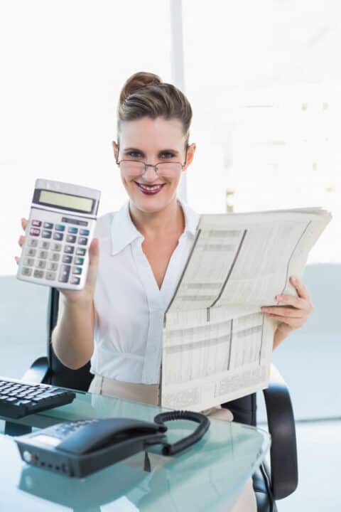 woman sitting in the office and holding calculator and newspapers